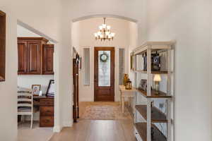 Foyer featuring light wood finished floors, arched walkways, a high ceiling, a chandelier, and built in study area