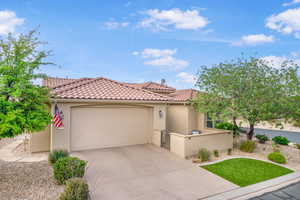 View of front of home featuring driveway, stucco siding, a garage, and a tiled roof
