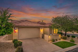 Mediterranean / spanish-style home featuring a garage, driveway, stucco siding, and a tile roof