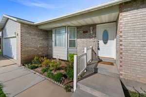 Entrance to property with brick siding, a garage, and concrete driveway