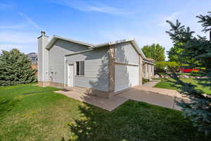 View of home's exterior with a yard, an attached garage, a chimney, and concrete driveway