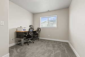 Office area featuring light carpet and a textured ceiling