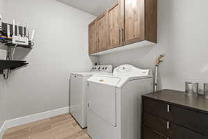 Laundry room with cabinet space, wood tiled floors, and washer and dryer