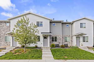View of front of property featuring stucco siding, stone siding, and a front lawn