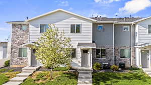 Townhome featuring stone siding and a front yard
