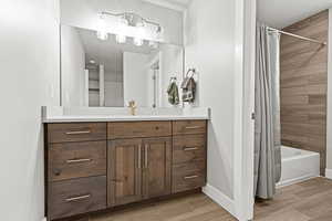 Bathroom with vanity, wood finish floors, and shower / bath combination with curtain