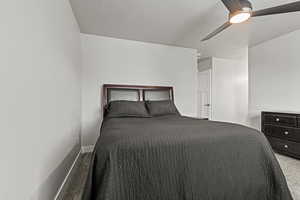 Carpeted bedroom with a ceiling fan and a textured ceiling