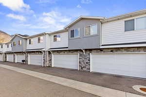 View of front of house with stone siding, a garage, and stucco siding