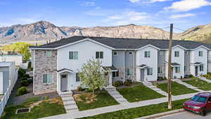 Traditional home featuring stone siding, a mountain view, a residential view, and a front yard
