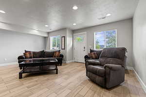 Living area featuring a textured ceiling, wood finish floors, and recessed lighting