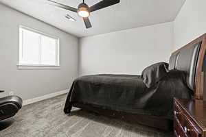 Bedroom with light colored carpet, a textured ceiling, and ceiling fan