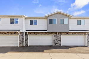 Traditional-style house featuring stone siding, an attached garage, and asphalt driveway