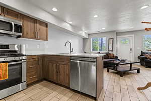 Kitchen with a peninsula, stainless steel appliances, wood tiled floors, a textured ceiling, and open floor plan