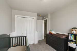 Bedroom featuring a closet, light carpet, and a wainscoted wall