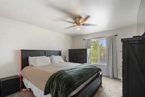 Carpeted bedroom featuring ceiling fan and baseboards