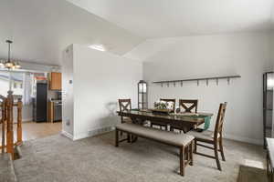 Dining area featuring light colored carpet, hanging lights, and lofted ceiling