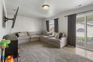 Living area with light tile patterned flooring and light colored carpet