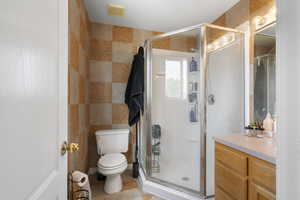 Bathroom featuring a shower stall, tile walls, and vanity