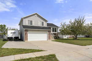 View of front of house featuring concrete driveway, an attached garage, a front yard, and brick siding