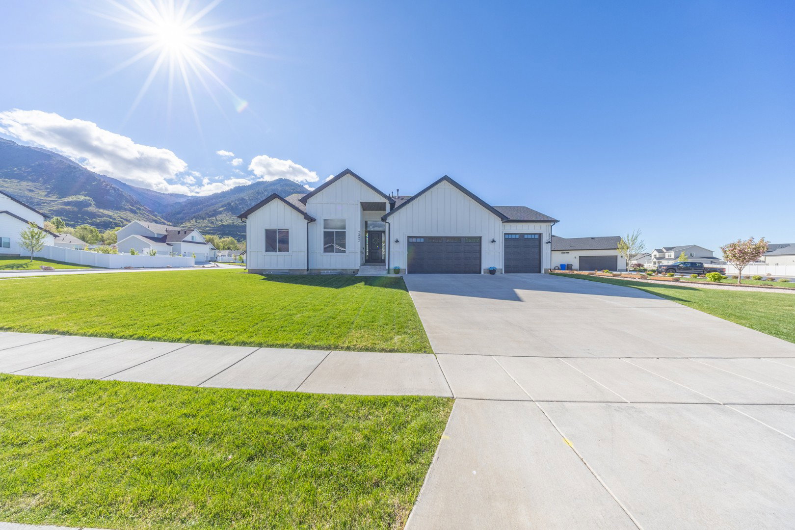 Modern farmhouse featuring a mountain view, board and batten siding, a front yard, and an attached garage