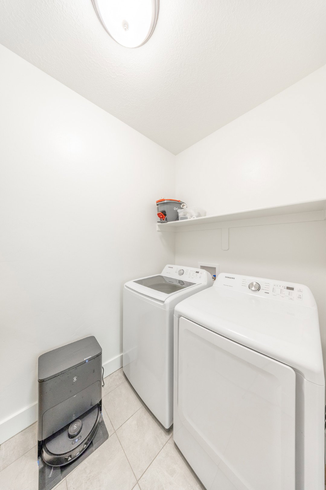 Laundry room with washing machine and clothes dryer and light tile patterned flooring