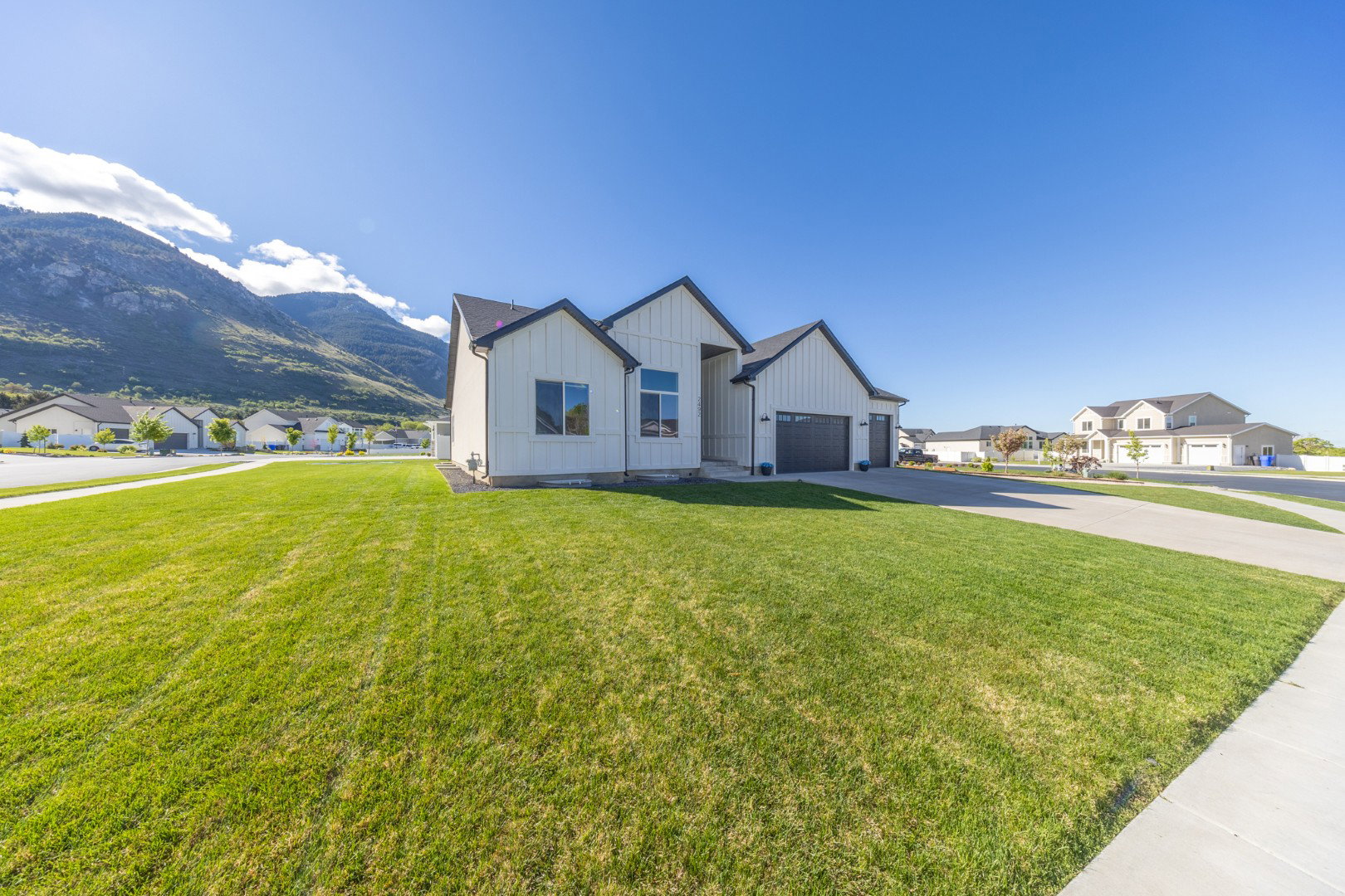 Modern inspired farmhouse featuring board and batten siding, a residential view, a mountain view, and a front yard