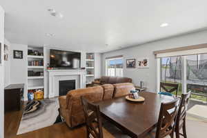 Dining space featuring built in shelves, wood finished floors, a fireplace, a textured ceiling, and recessed lighting