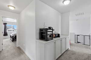 Corridor featuring light carpet and a textured ceiling