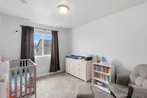 Bedroom featuring light carpet and a crib