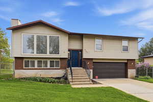 Bi-level home featuring an attached garage, brick siding, and driveway