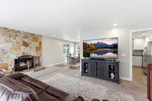 Living room with a fireplace, light colored carpet, and recessed lighting