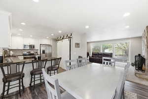 Dining room featuring dark wood-style floors, a barn door, and recessed lighting