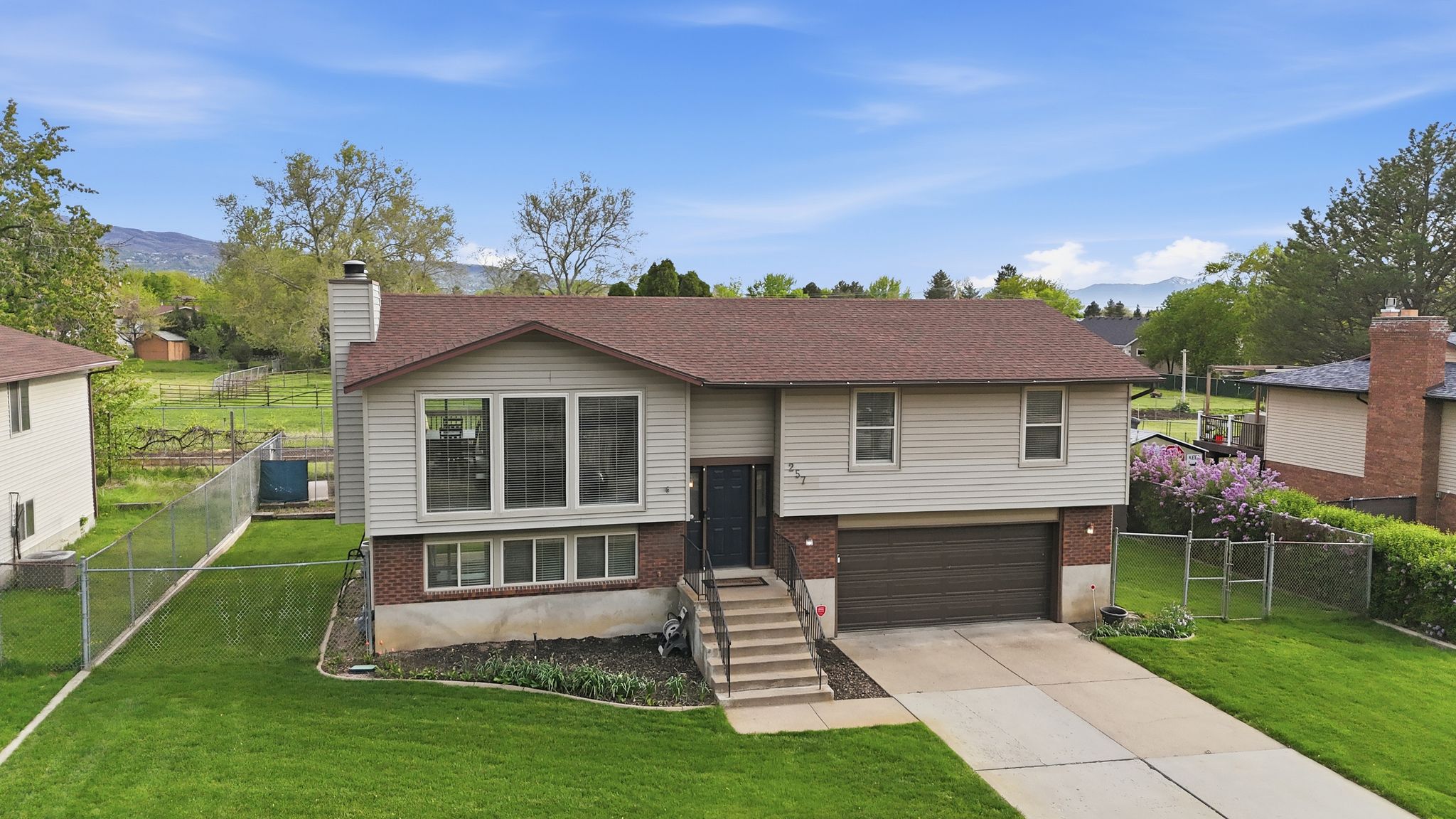 Split foyer home featuring brick siding, an attached garage, concrete driveway, and a gate