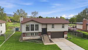 Split foyer home featuring brick siding, an attached garage, concrete driveway, and a gate
