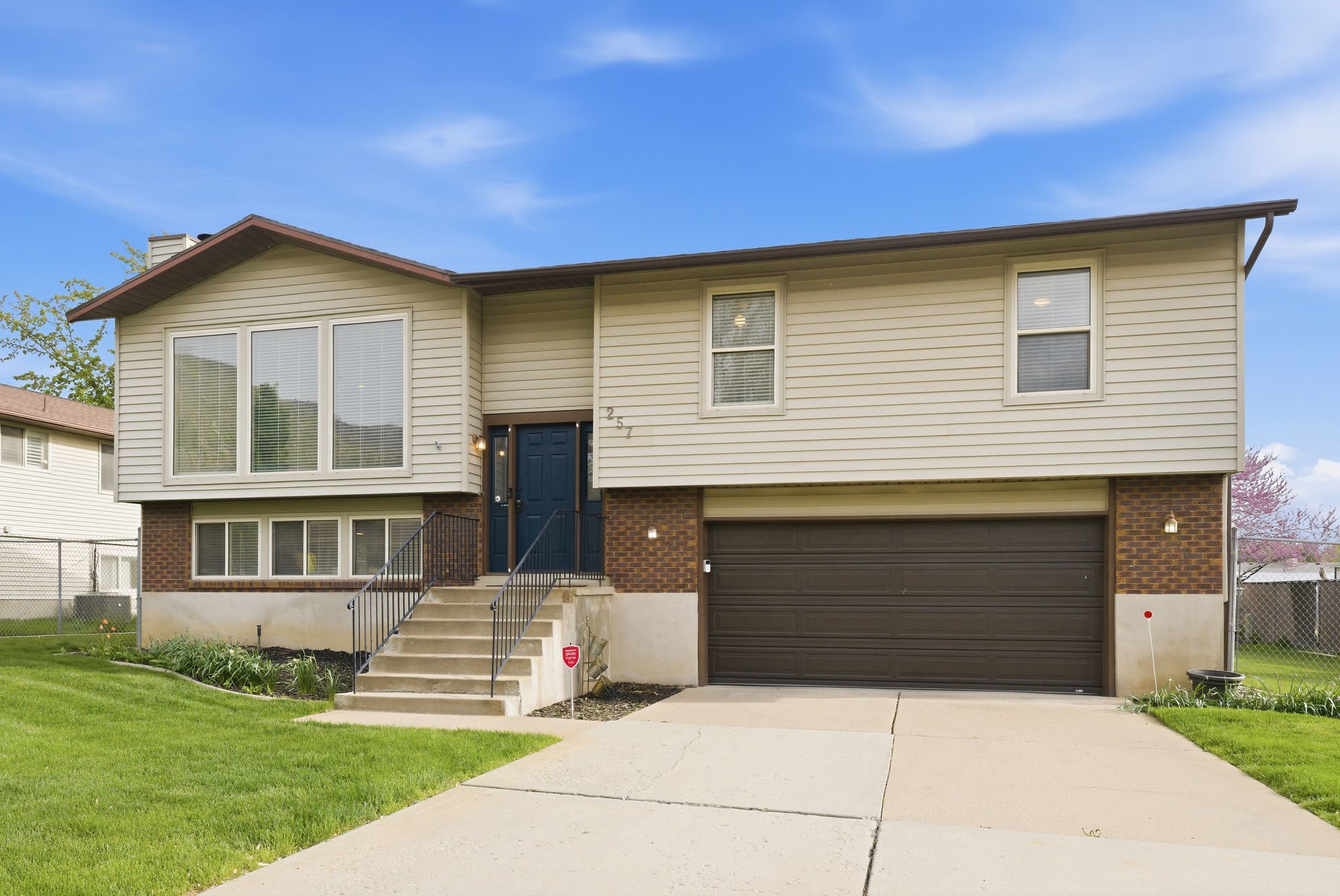 Bi-level home featuring brick siding, an attached garage, a front yard, and driveway