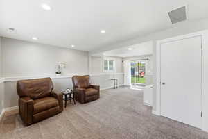 Living area featuring light colored carpet and recessed lighting