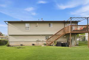 Back of house featuring a yard, a wooden deck, and a patio area