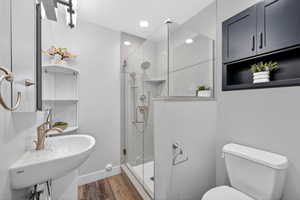 Bathroom with a shower stall, dark wood-style floors, and recessed lighting