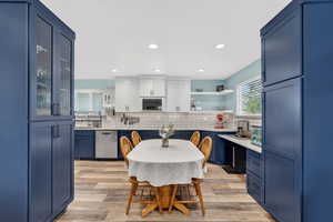 Dual tone kitchen featuring open shelves, light wood-style floors, stainless steel dishwasher, dual tone cabinets, and recessed lighting