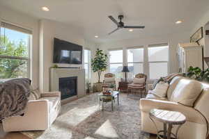 Living area with a ceiling fan, a glass covered fireplace, recessed lighting, and wood finished floors