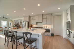 Kitchen featuring gray cabinetry, a breakfast bar, stainless steel appliances, light wood-style flooring, and recessed lighting