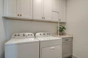 Laundry room featuring independent washer and dryer and cabinet space