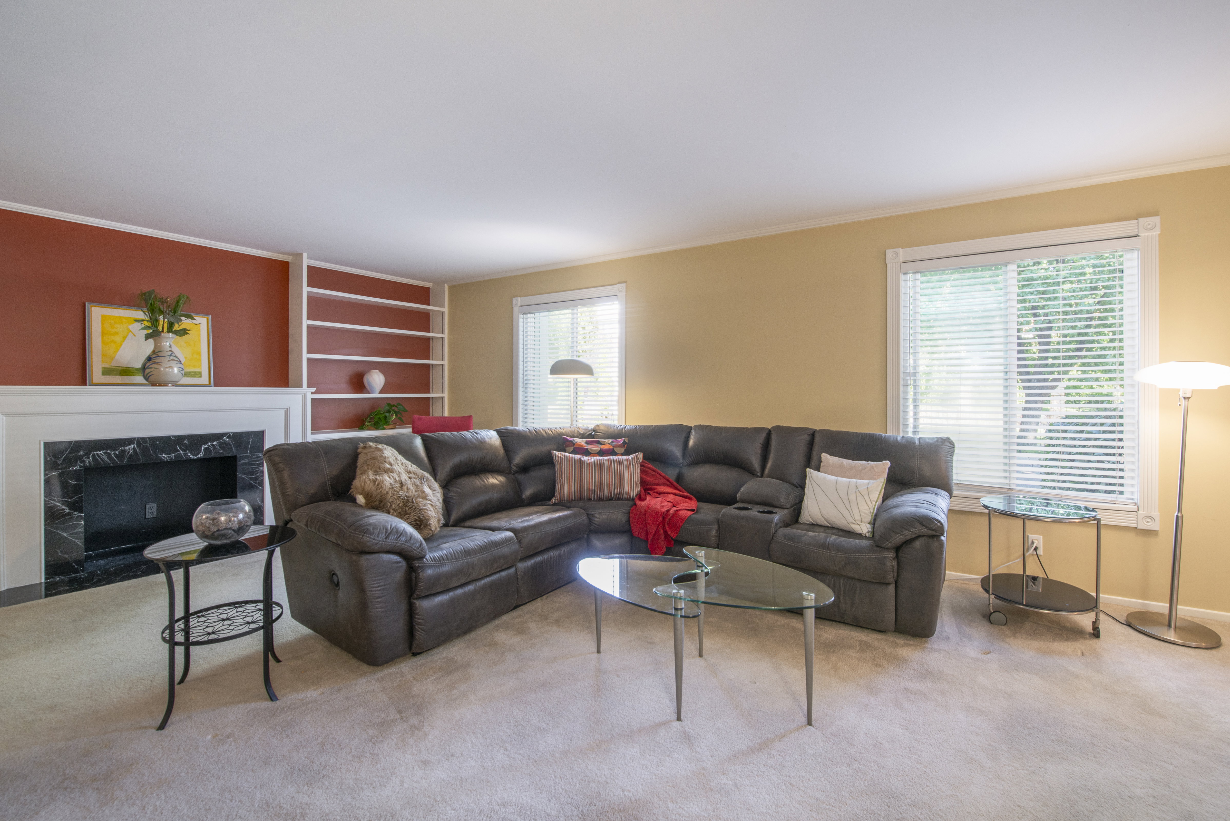 Carpeted living area featuring a fireplace, plenty of natural light, built in shelves, and ornamental molding