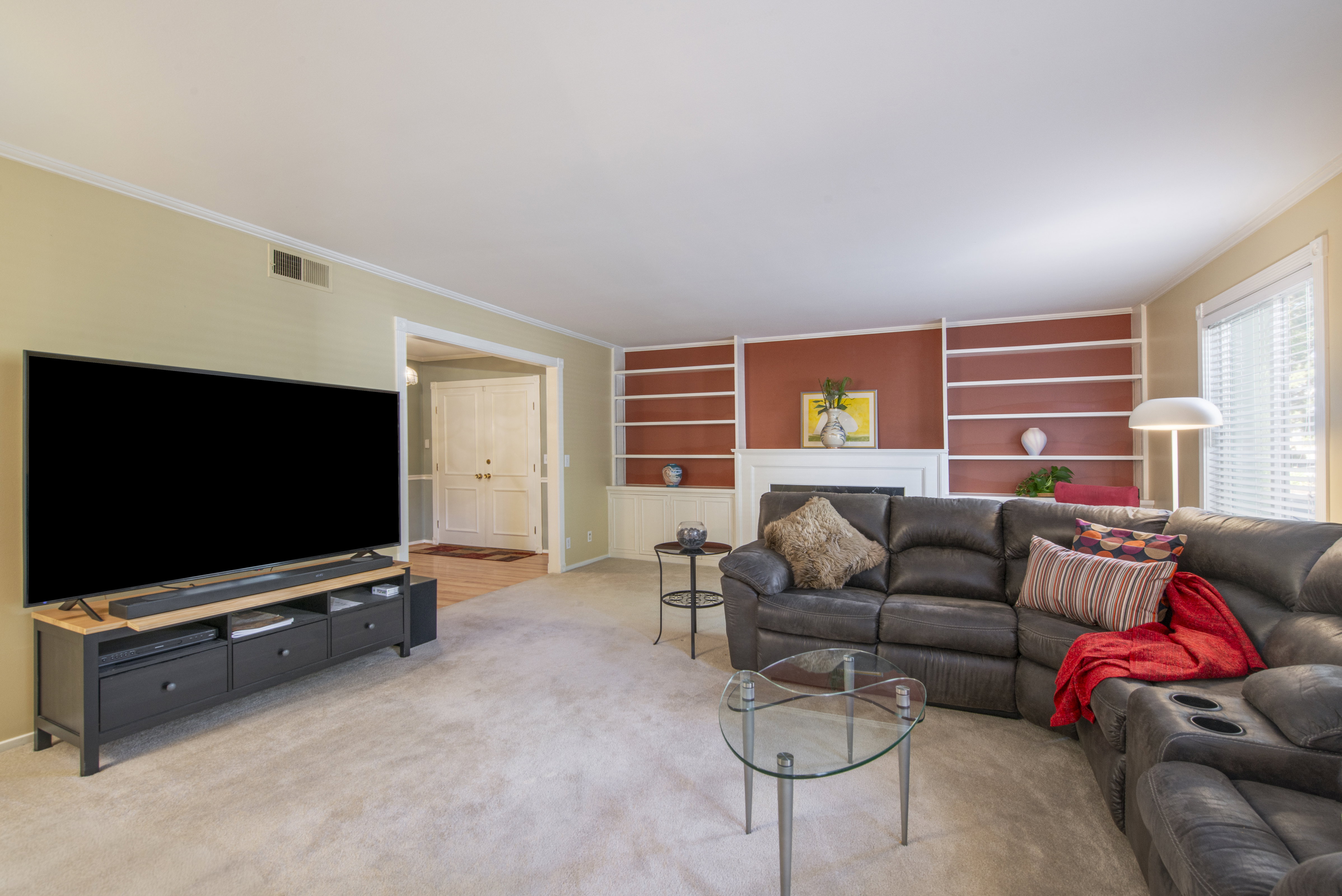 Living area with built in shelves, ornamental molding, light carpet, and a fireplace