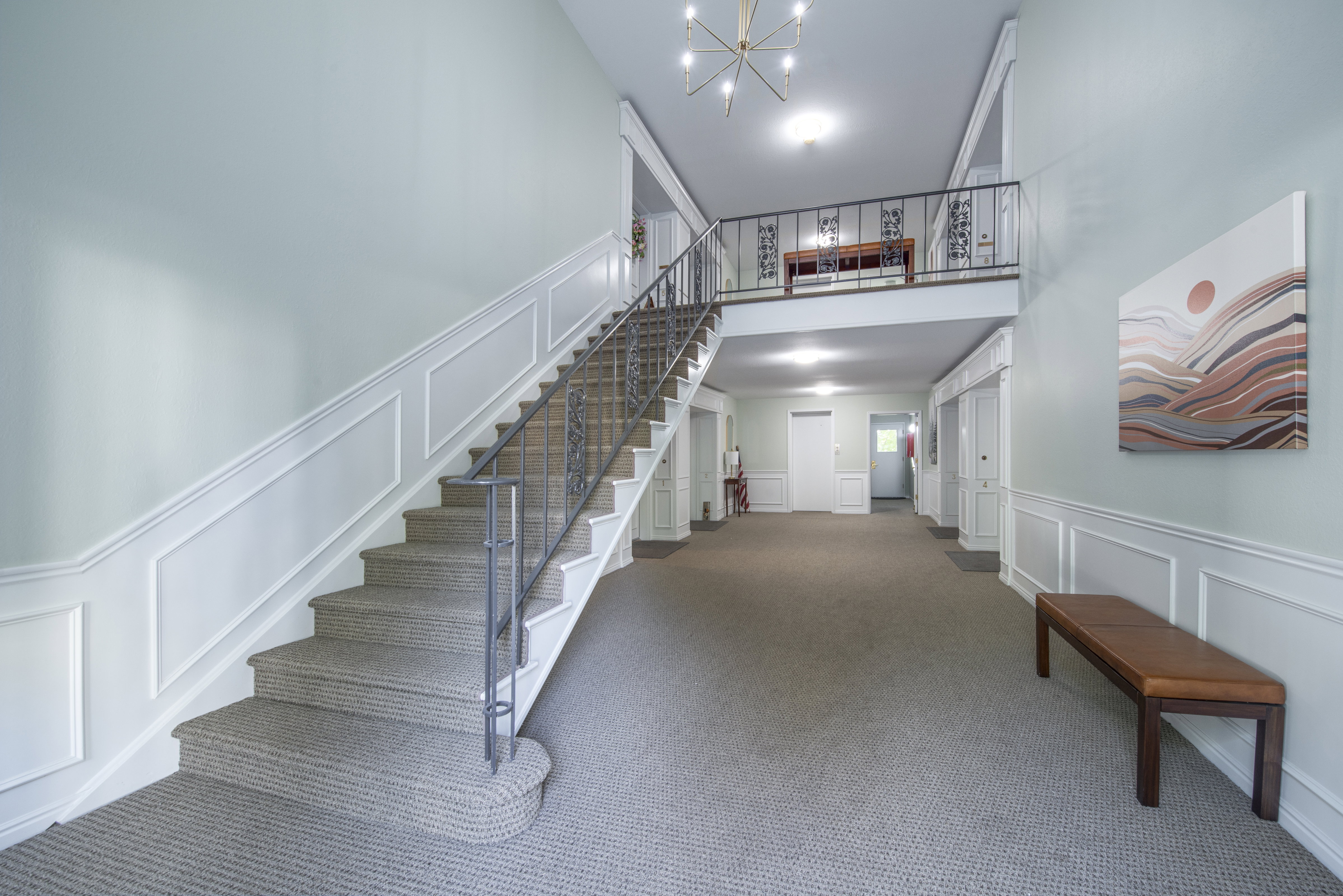 Stairway featuring a decorative wall, a chandelier, wainscoting, and carpet
