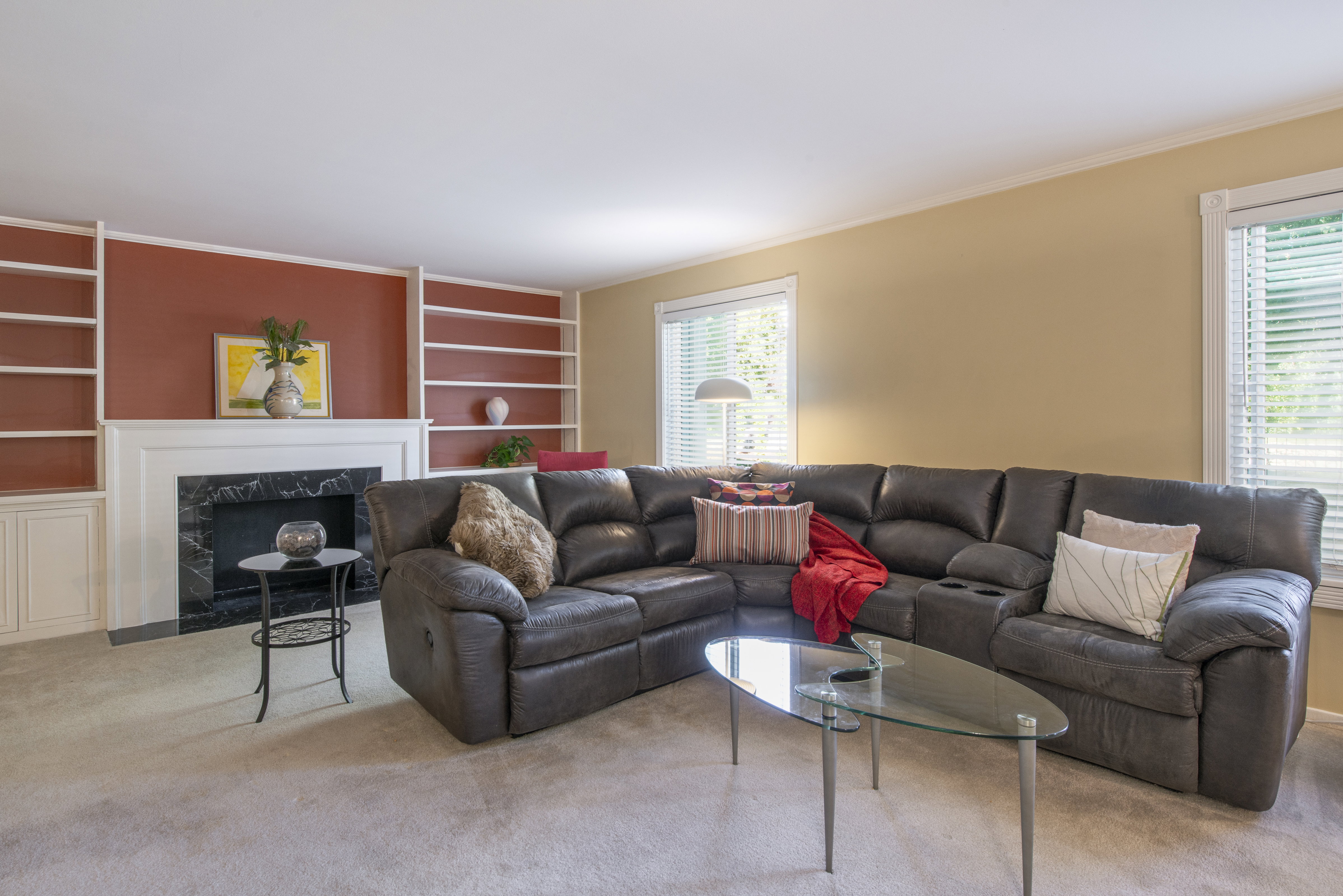 Carpeted living room with built in features, plenty of natural light, a fireplace, and ornamental molding