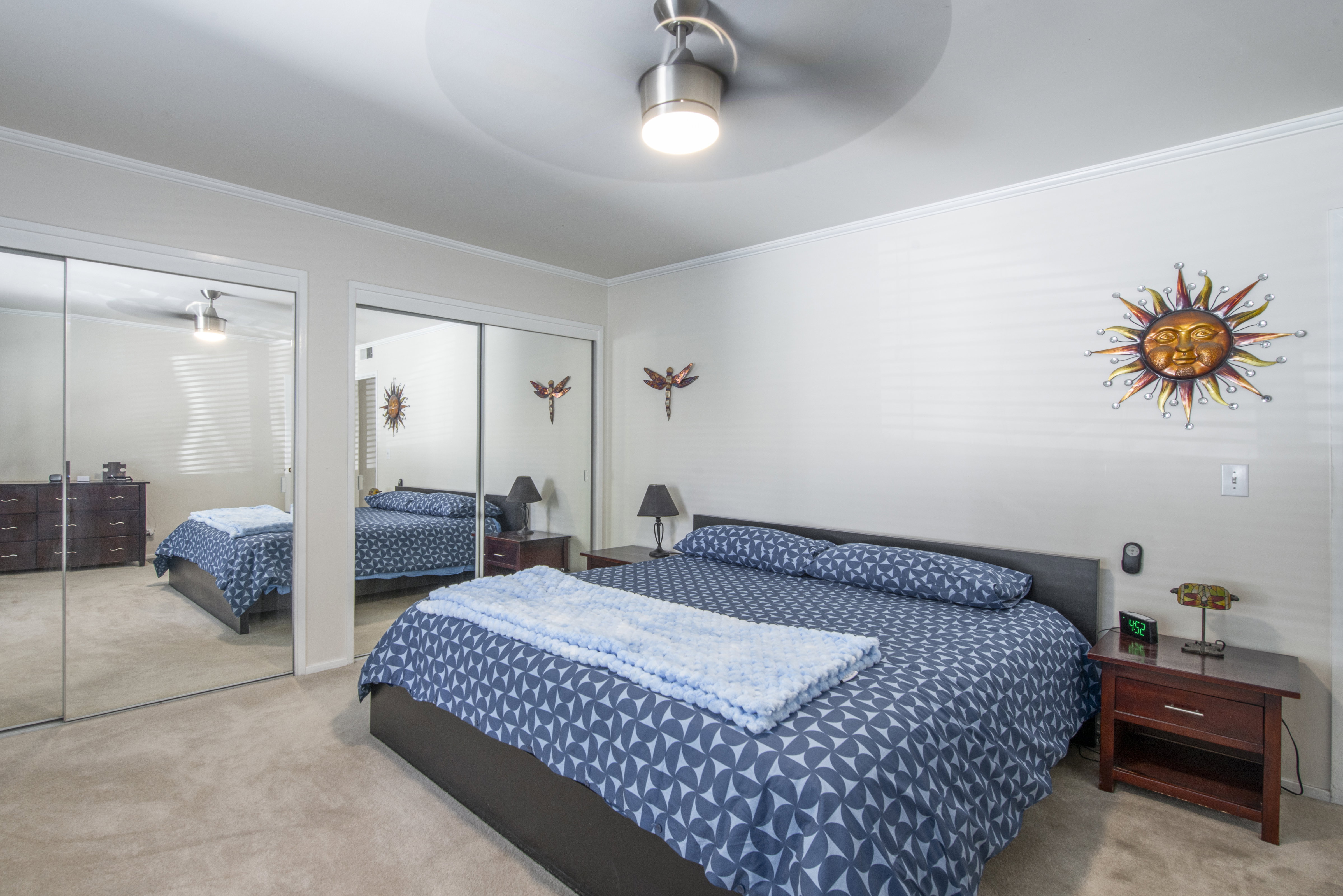 Bedroom with multiple closets, light carpet, crown molding, and a ceiling fan