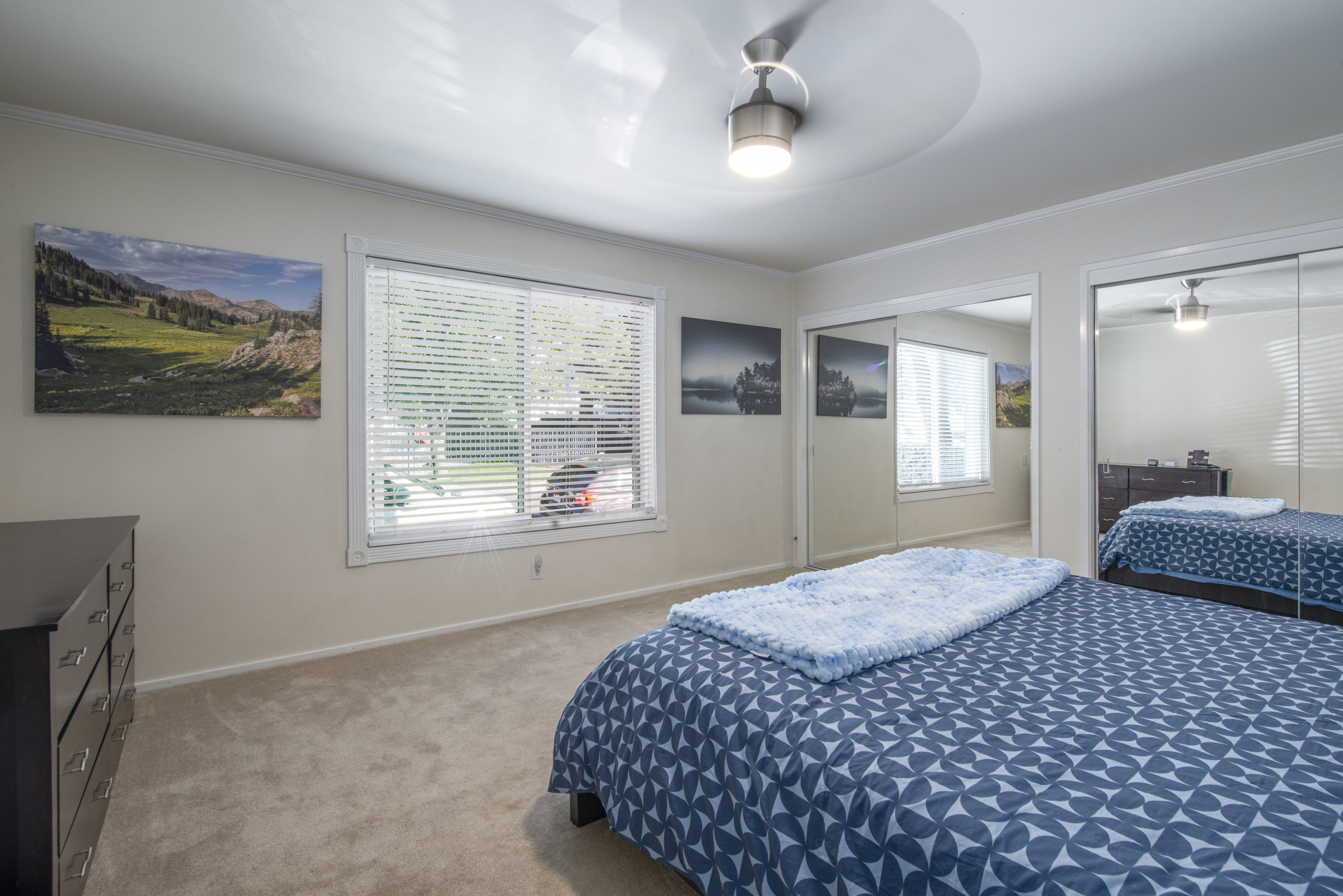 Bedroom featuring two closets, light colored carpet, ceiling fan, and ornamental molding