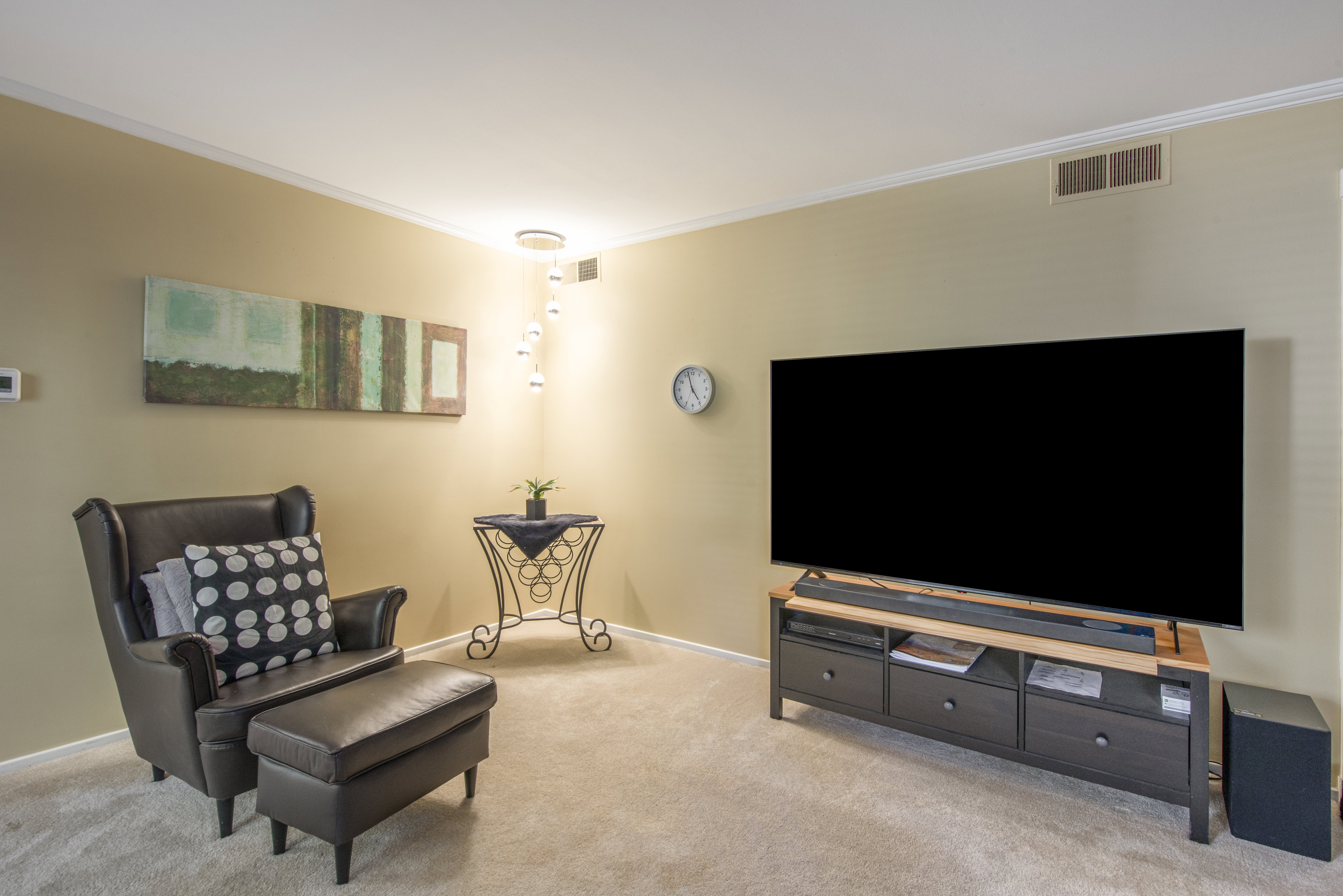 Living area with crown molding and light colored carpet