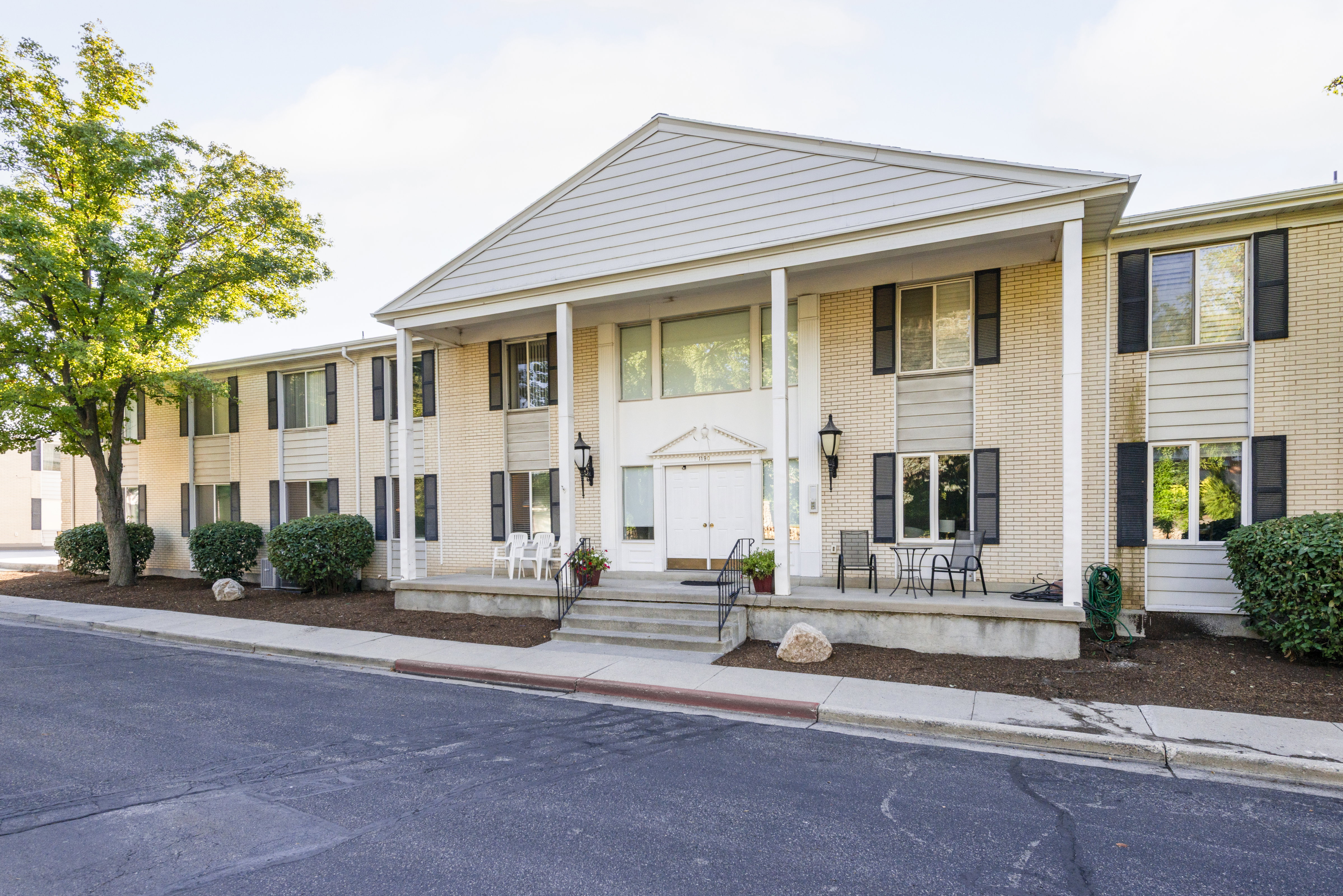 Greek revival inspired property featuring a porch and brick siding